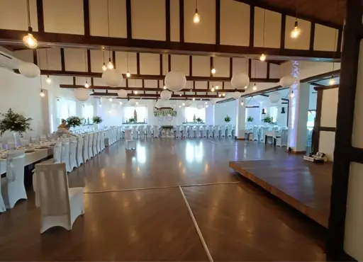 Sala weselna z białymi pokrowcami i parkietem